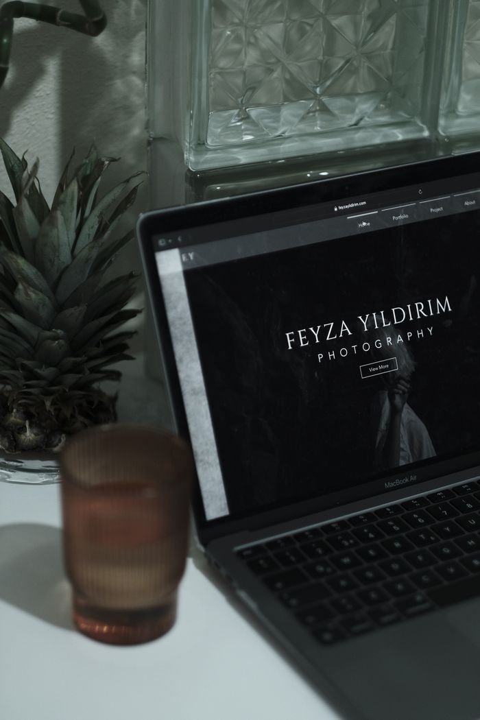 An aesthetically pleasing workspace featuring a laptop with a photographer's website, surrounded by minimalist decor.